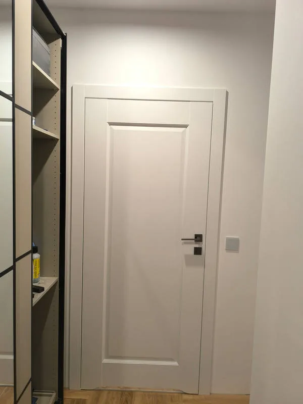 Białe drzwi z czarną klamką